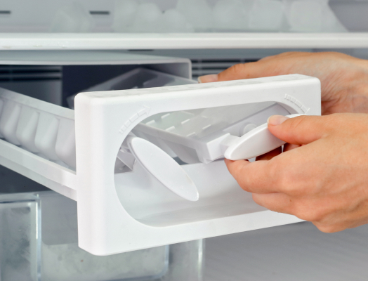 Two hands removing ice maker racks filled with solid frozen ice, highlighting affresh® ice machine cleaning product.