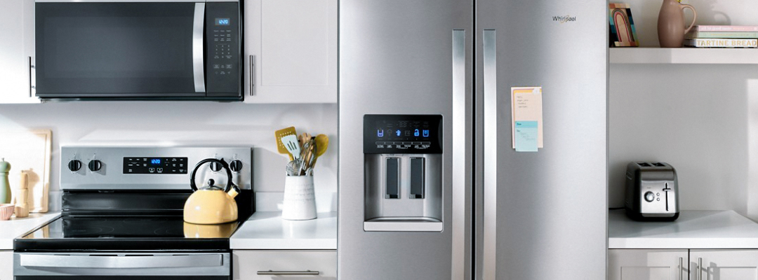 Modern kitchen with a stainless steel refrigerator, digital water and ice maker, black-and-silver stove with a yellow teapot, black microwave, and clean white counters, conveying a sleek and tidy ambiance.