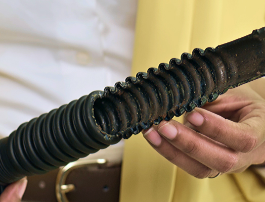 A person holding a dirty washing machine drain hose with visible buildup, highlighting the need for cleaning and sanitizing.