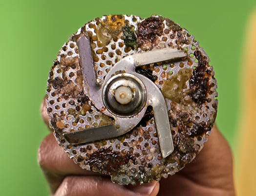 ​​Close-up of a dirty dishwasher chopper screen covered in food debris and buildup, highlighting the need for regular cleaning with affresh® dishwasher cleaner.