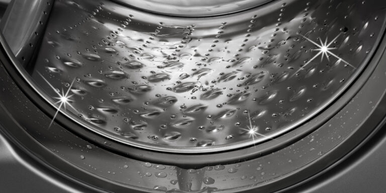 A sparkling clean washing machine drum with droplets of water, illustrating the effectiveness of affresh® cleaning products.