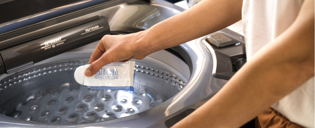 Affresh® washing machine cleaner tablet being added to top load washer to help remove soap scum, odors and buildup